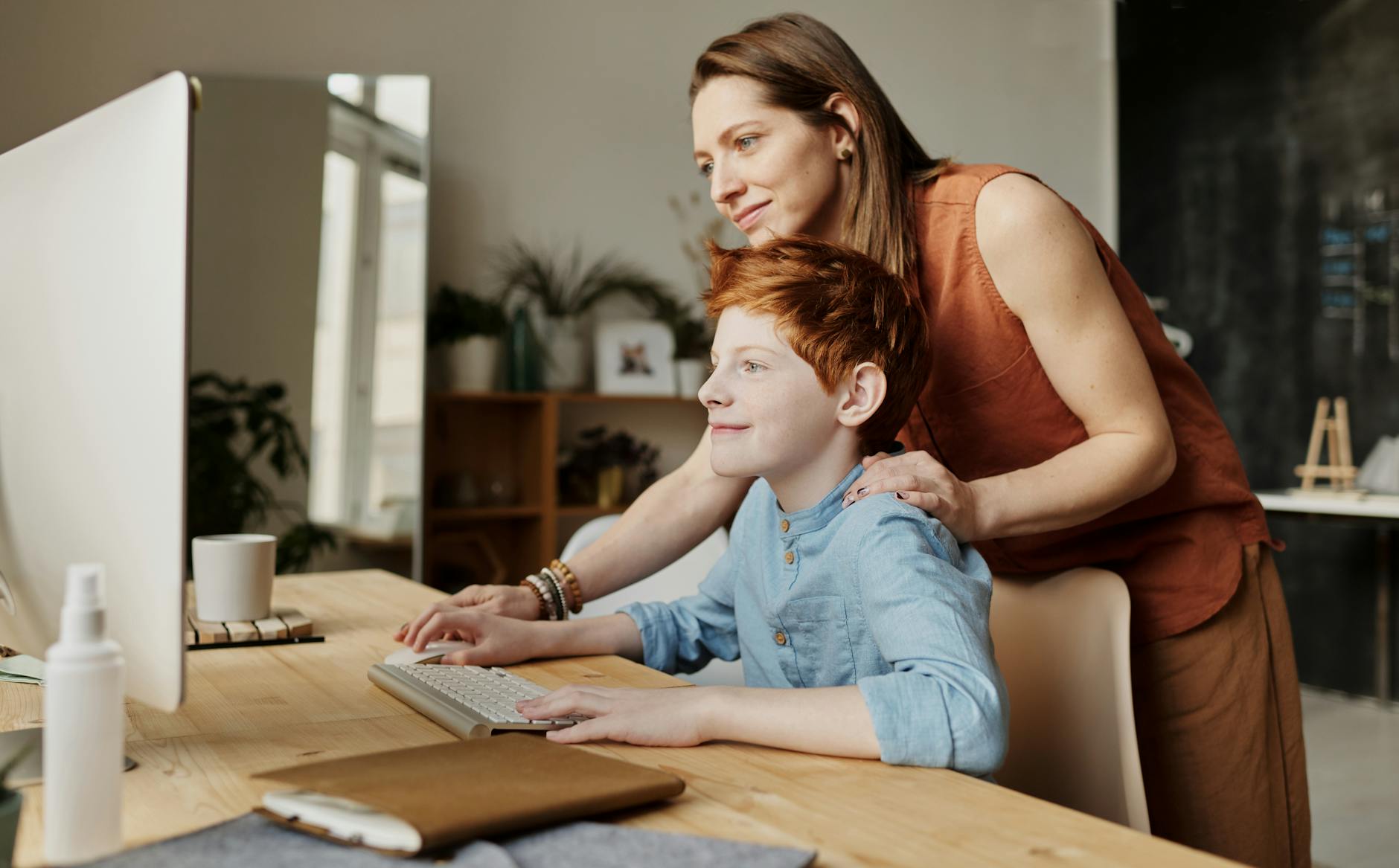 photo of woman helping her son log in the computer for a virtual psychiatric appointment